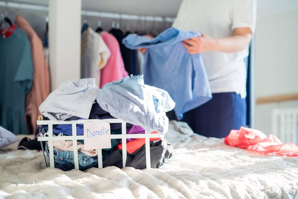 A generic photo of a person sorting clothes into a box with a label saying donate