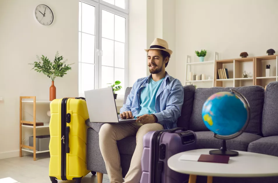 Man planning a holiday online, while sitting surrounded by suitcases