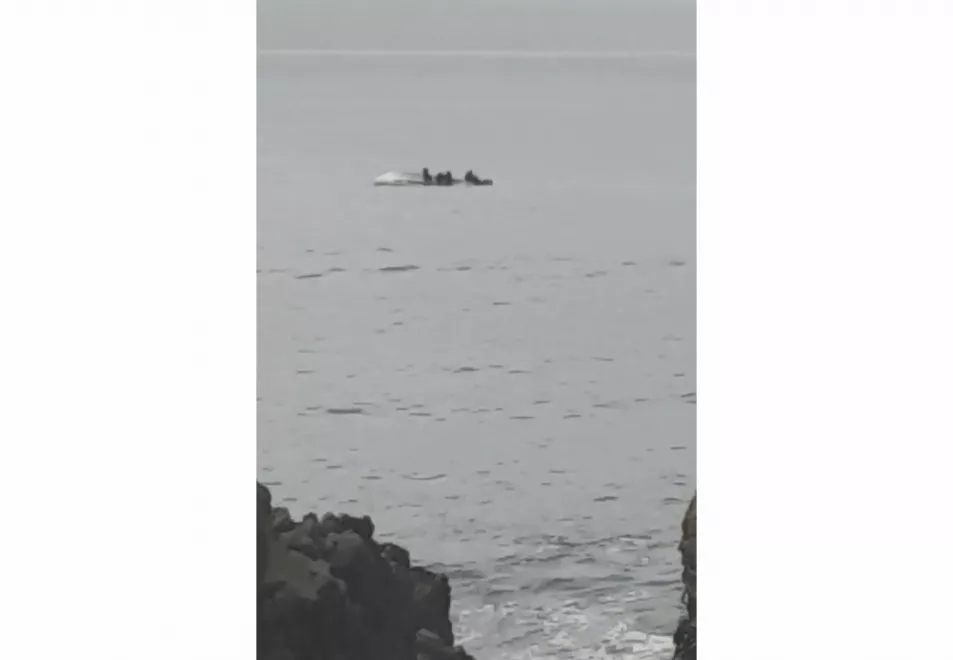 In this image taken from video, survivors cling to the upturned hull of a boat that capsized off the coast of Kaikoura, New Zealand