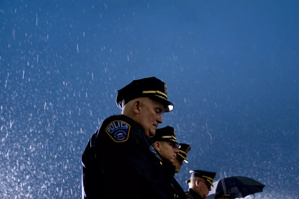 First responders and guests stand in the driving rain after a US flag is unfurled at the Pentagon
