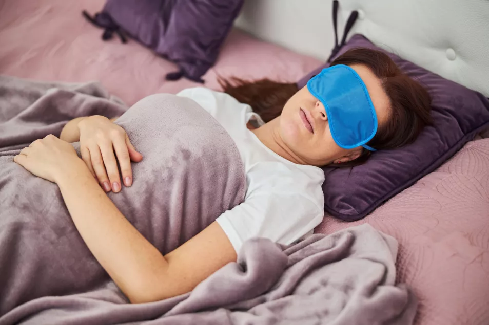 A woman in bed asleep with an eye mask on