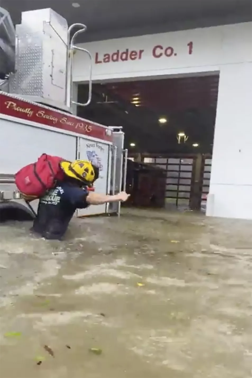 A firefighter carrying gear in water in Naples, Florida