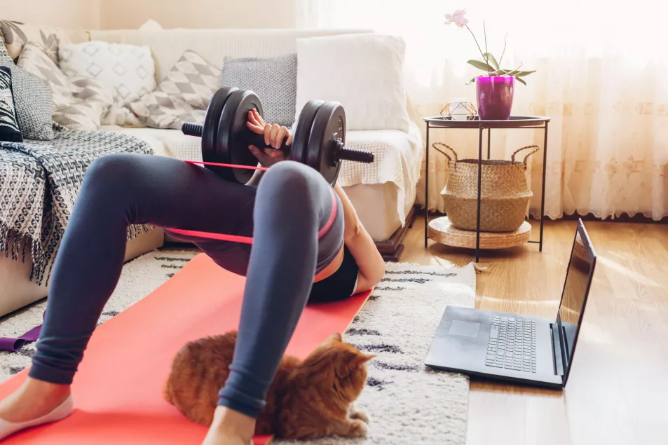A woman doing a home workout with weights in the living room