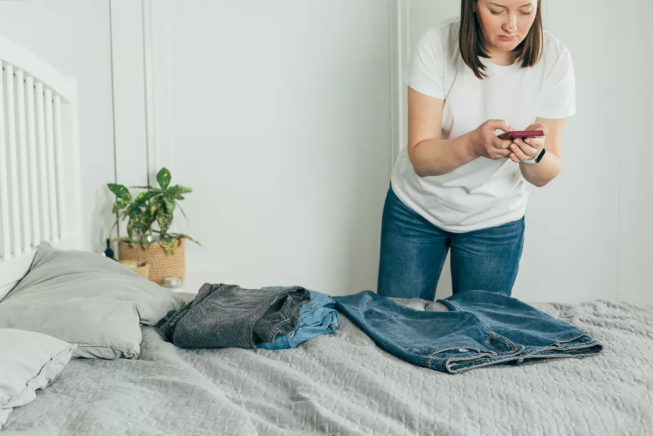 Woman taking photo of jeans on smartphone