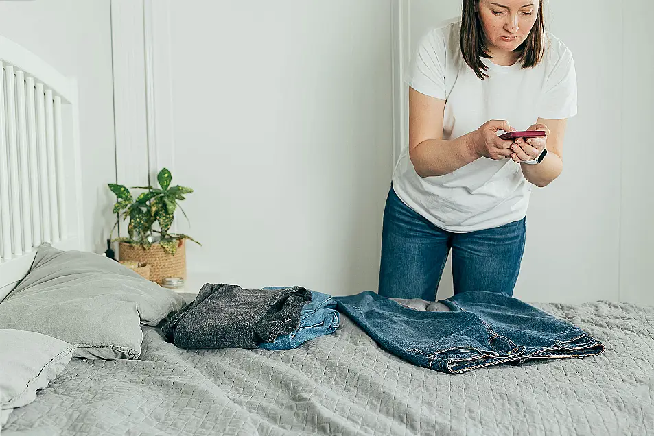 Woman taking photo of jeans on smartphone