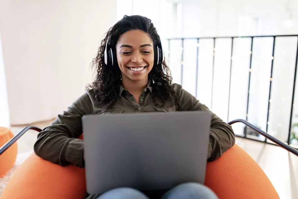 Woman with headphones and laptop, smiling