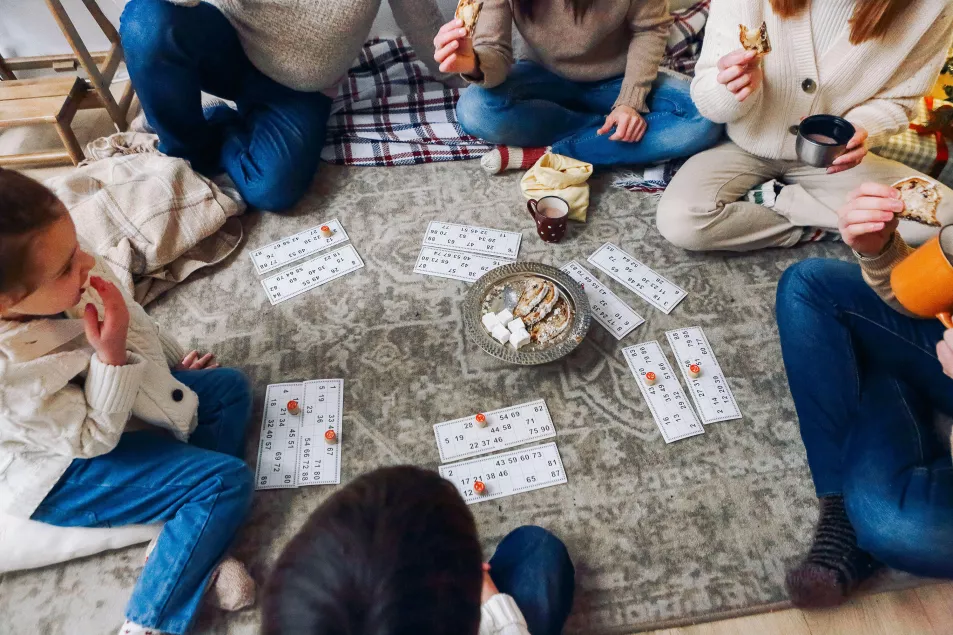 family with children sitting on floor playing lotto board game