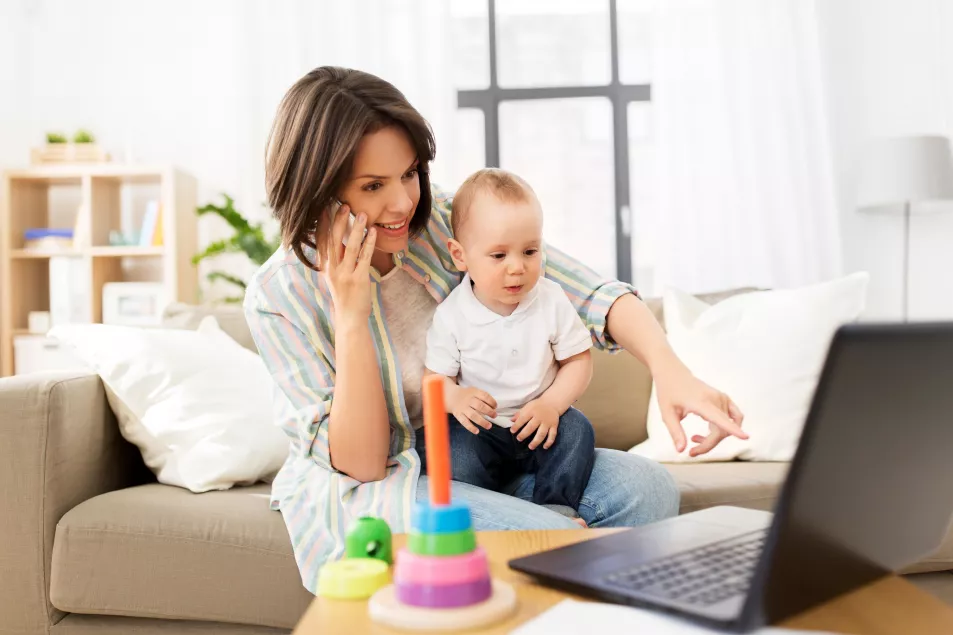Working mother with baby calling on smartphone