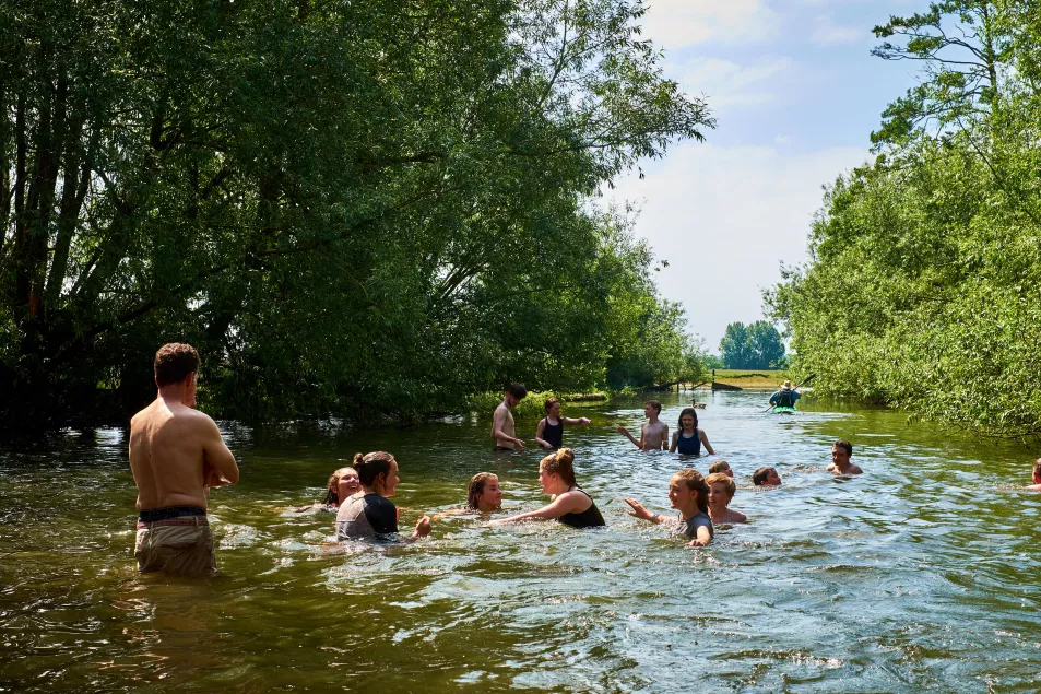 Adults and children play in the river Thames near Oxford on a hot summer day.