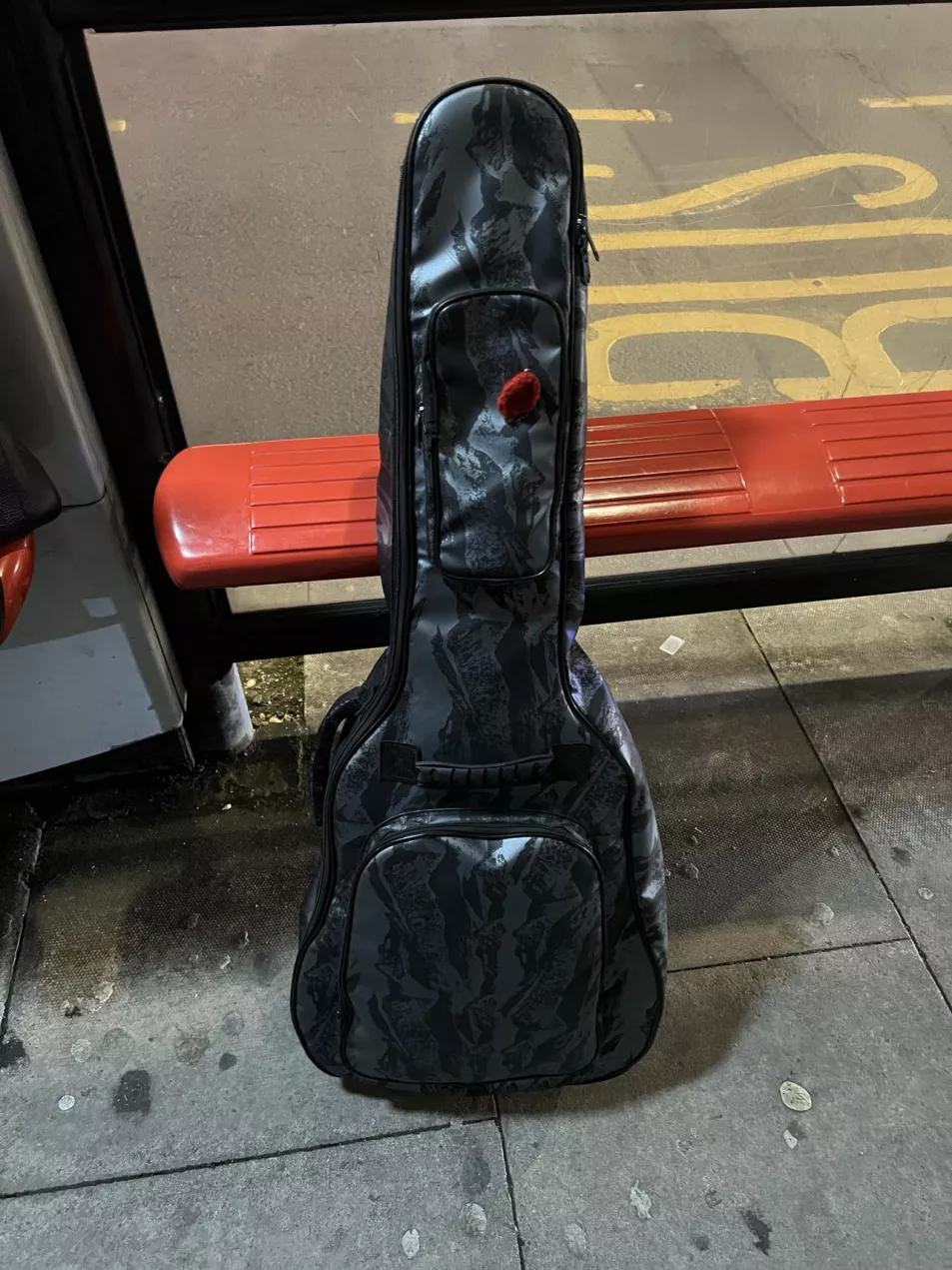 A photo of Jesse Geaney's guitar in a black case resting against the bus stop in south London where he left it