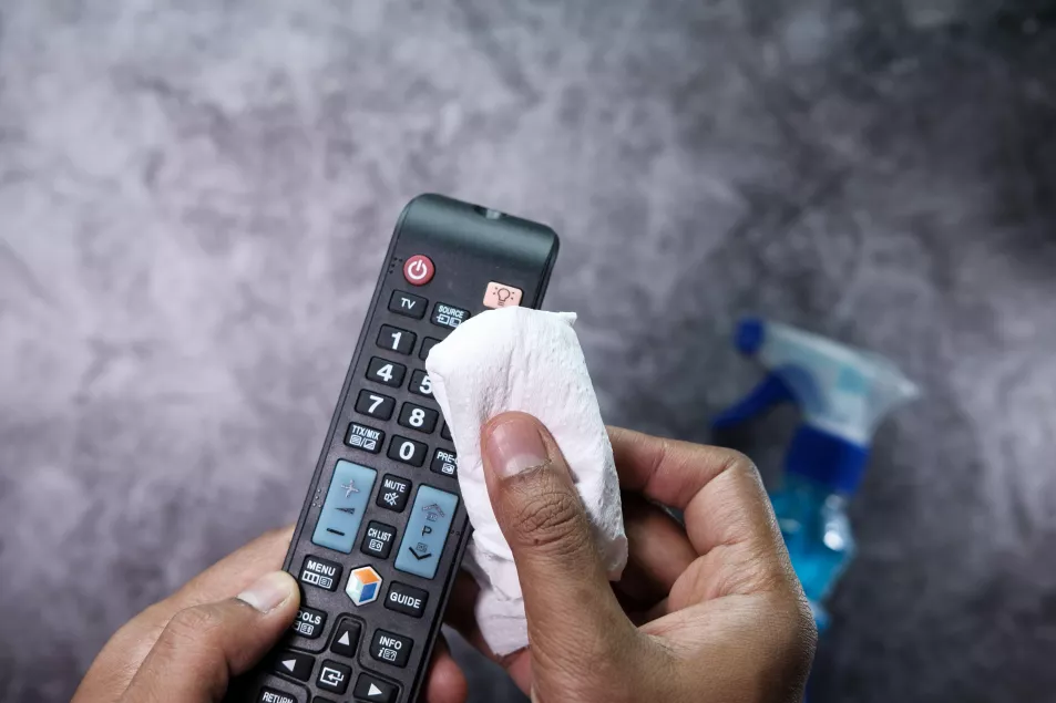 Man disinfecting TV remote control