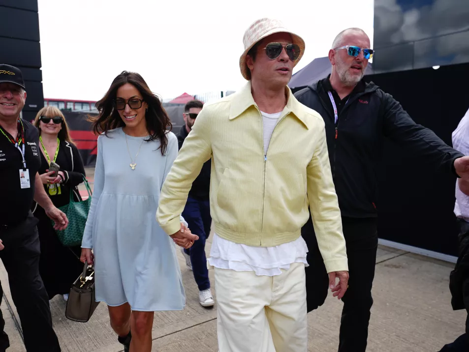 Брэд Питт в желтом костюме с розово-белой панамой вместе с Инес Де Рамон в бледно-голубом платье, когда они прибывают на трассу Гран-при Великобритании.
