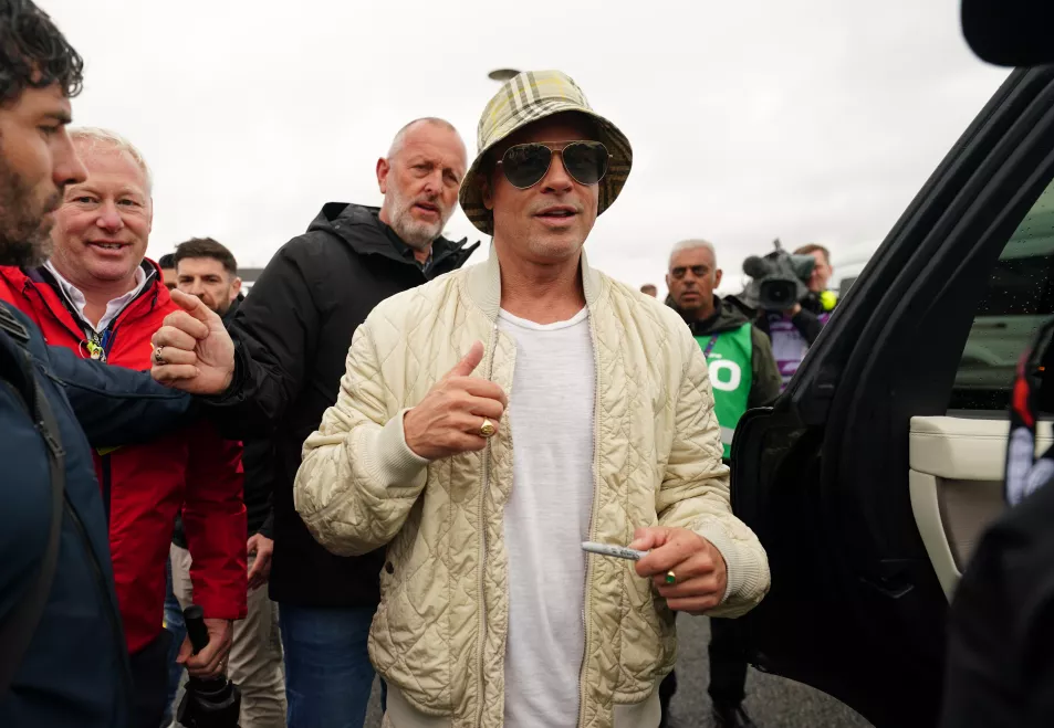 Брэд Питт в панаме Burberry, бежевой стеганой куртке и солнцезащитных очках-авиаторах во время прибытия на Гран-при Великобритании в субботу, 6 июля.