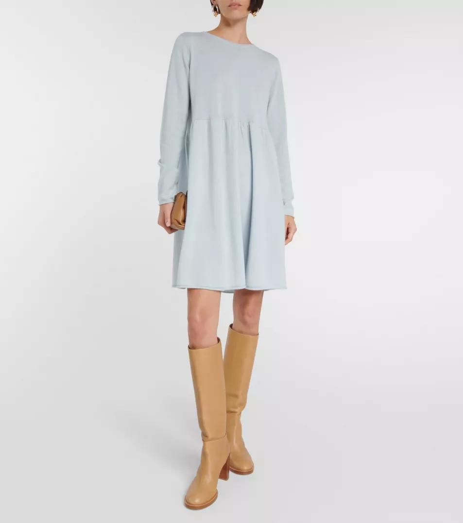На модели бледно-голубое хлопковое платье с длинными рукавами и коротким подолом.