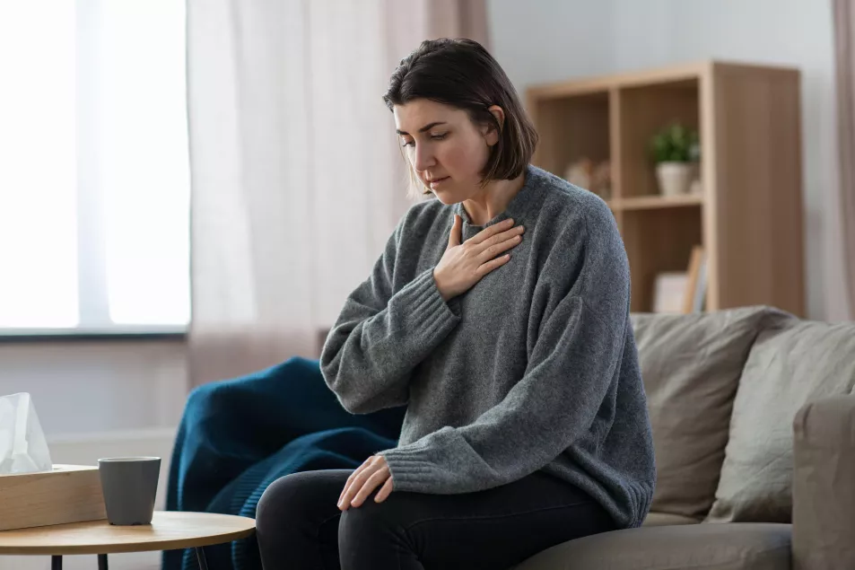 A young woman experiencing a panic attack while sat on the sofa at home 