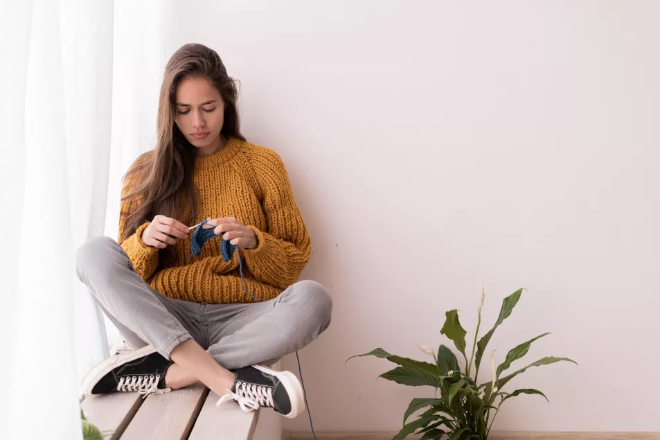 Woman sat on a window sill crocheting