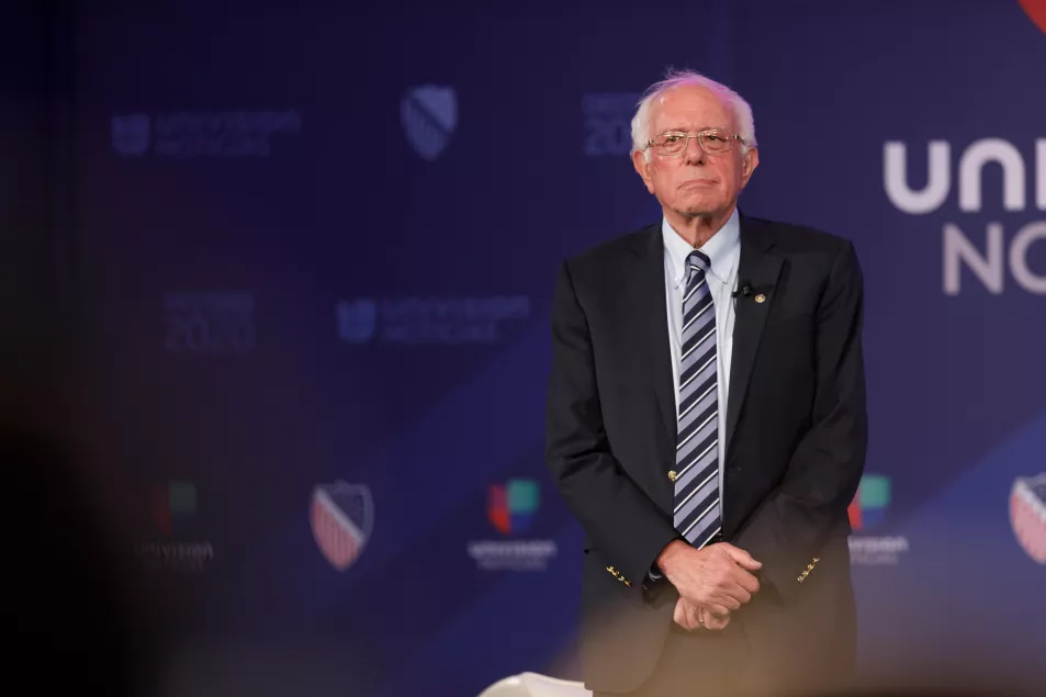 Bernie Sanders stands in a suit and tie