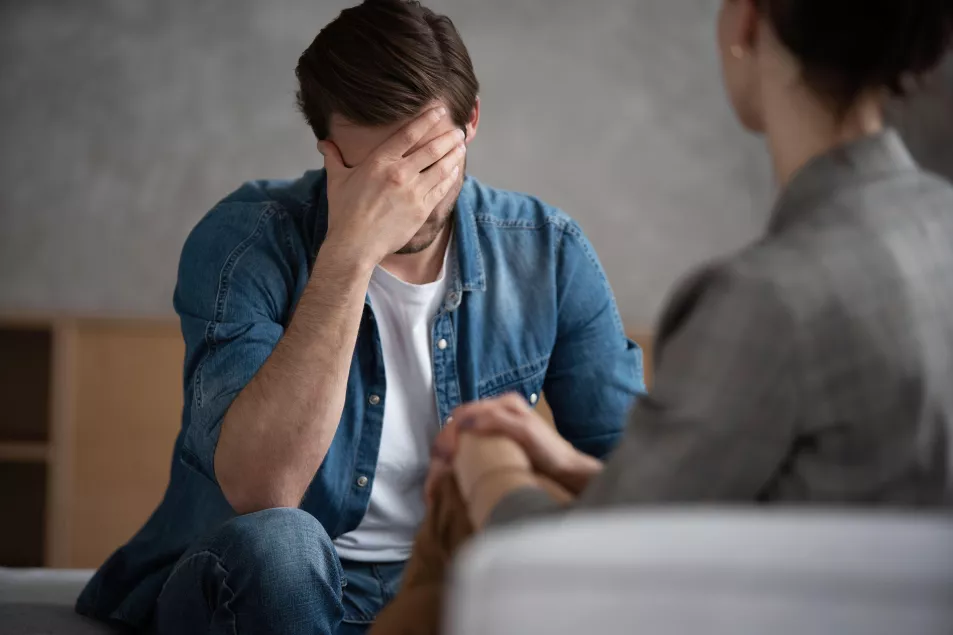 Depressed man speaking to a therapist while she is taking notes