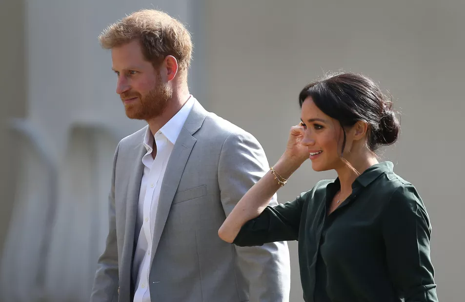 The Duke and Duchess of Sussex walk side by side 