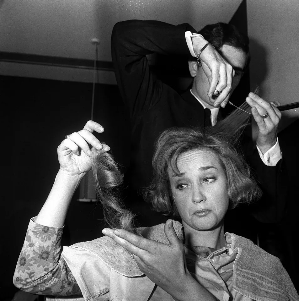 Vidal Sassoon cuts the hair of a woman as she catches her chopped locks