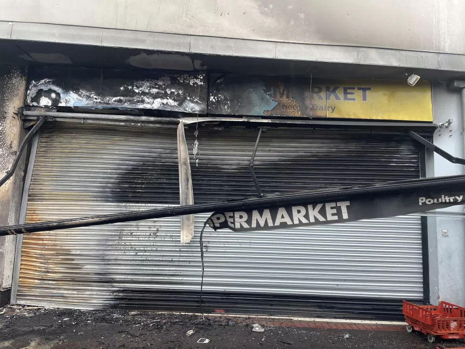 Shutters and sign above a business shows fire damage