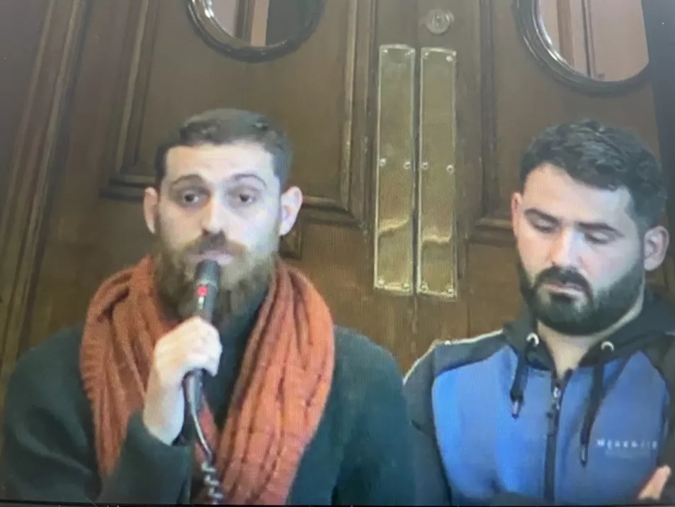 Two men, one speaking into a microphone in council chamber