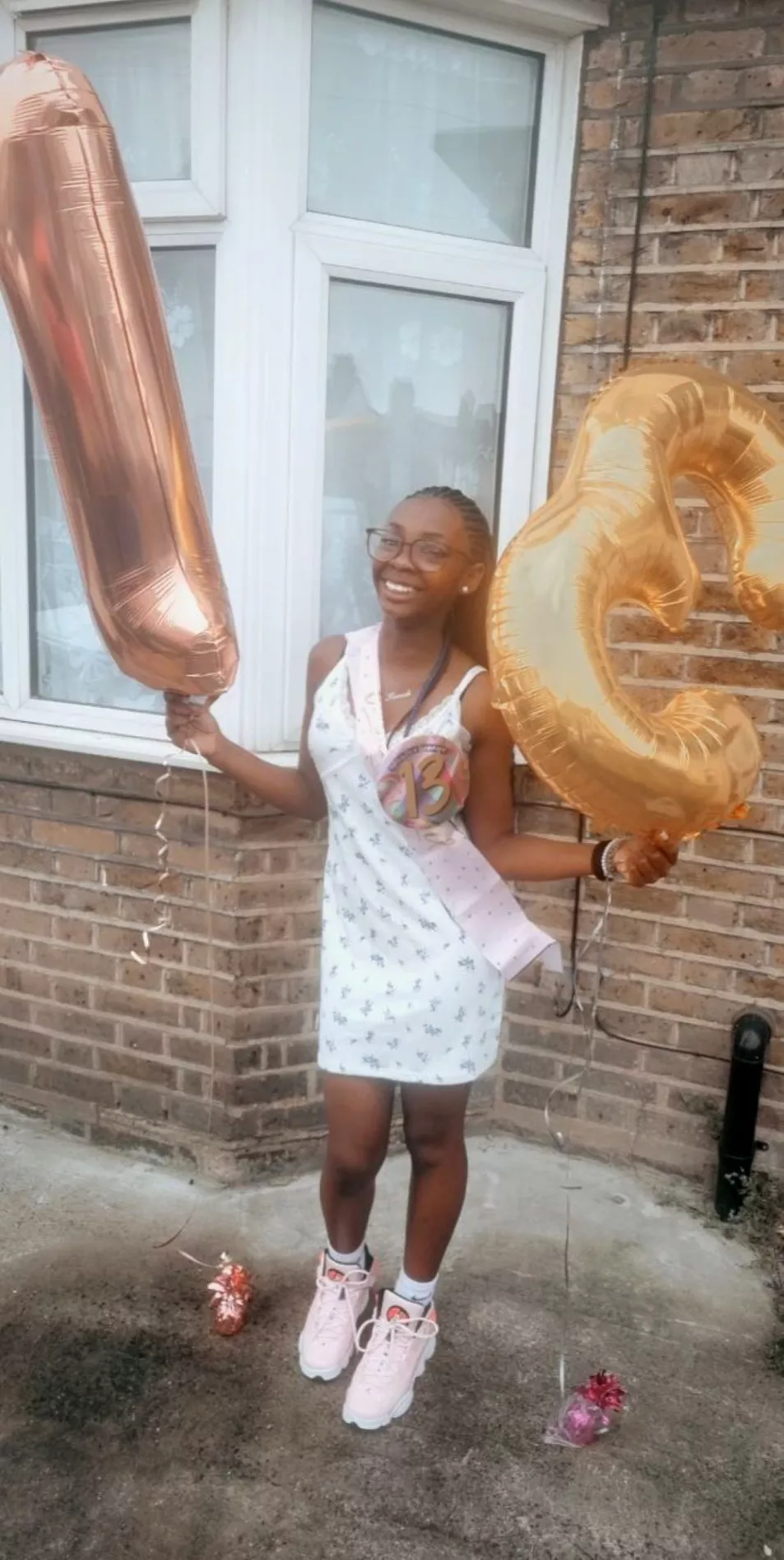 A smiling Hannah Jacobs holding birthday balloons that show the number 13