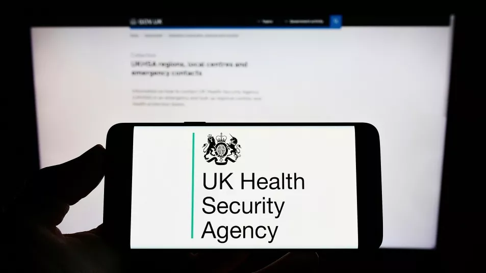 Person holding smartphone with logo of agency UK Health Security Agency (UKHSA) on screens