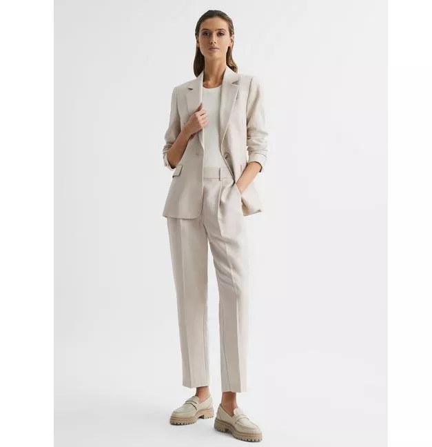 Model wears oatmeal tailored trousers and matching jacket with white T-Shirt