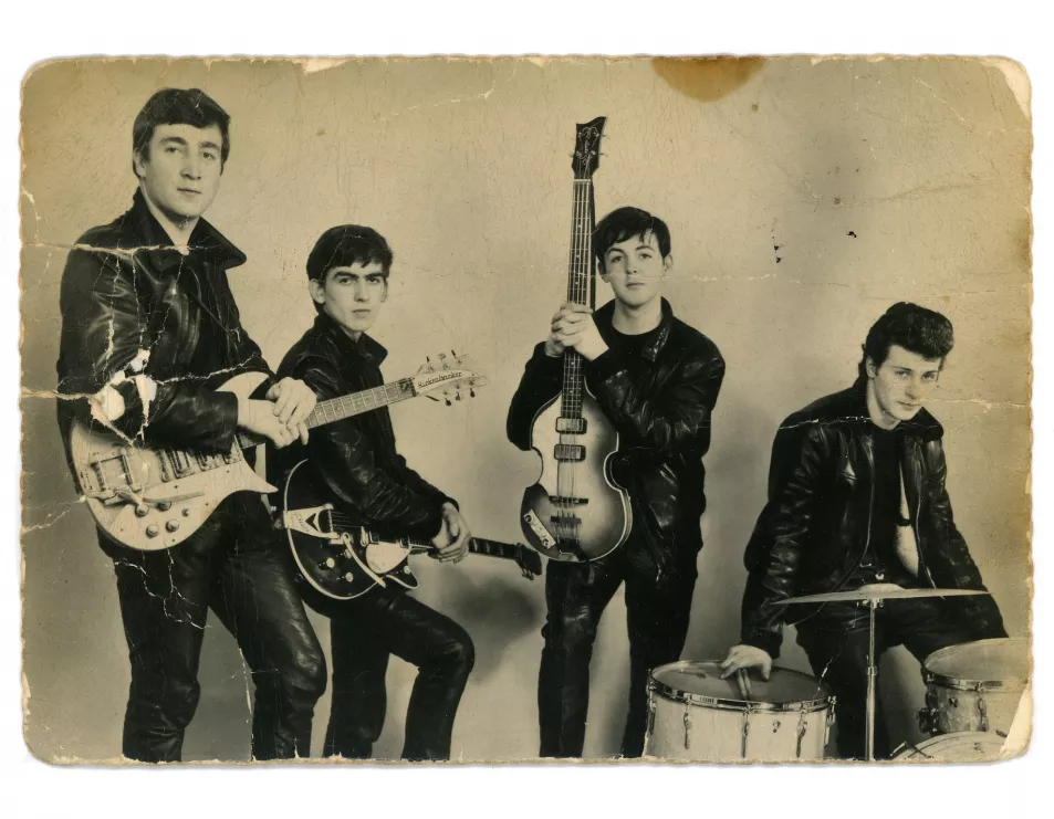 The BEatles pose in leather jackets and quaffed hair with their guitars and drums