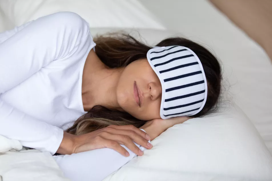 Woman falls asleep with eye mask on in bed