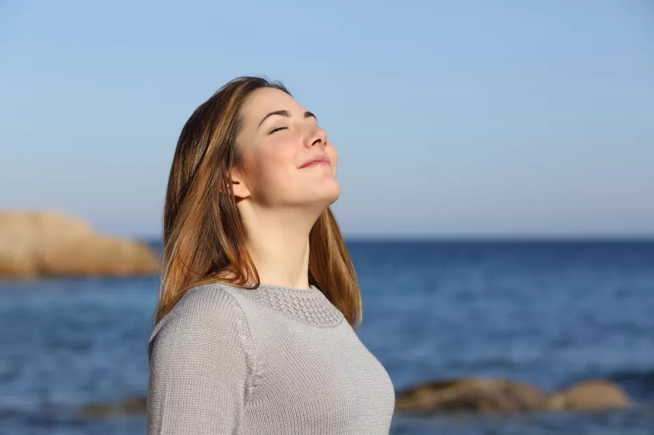 Happy relaxed woman breathing deep fresh air on the beach 