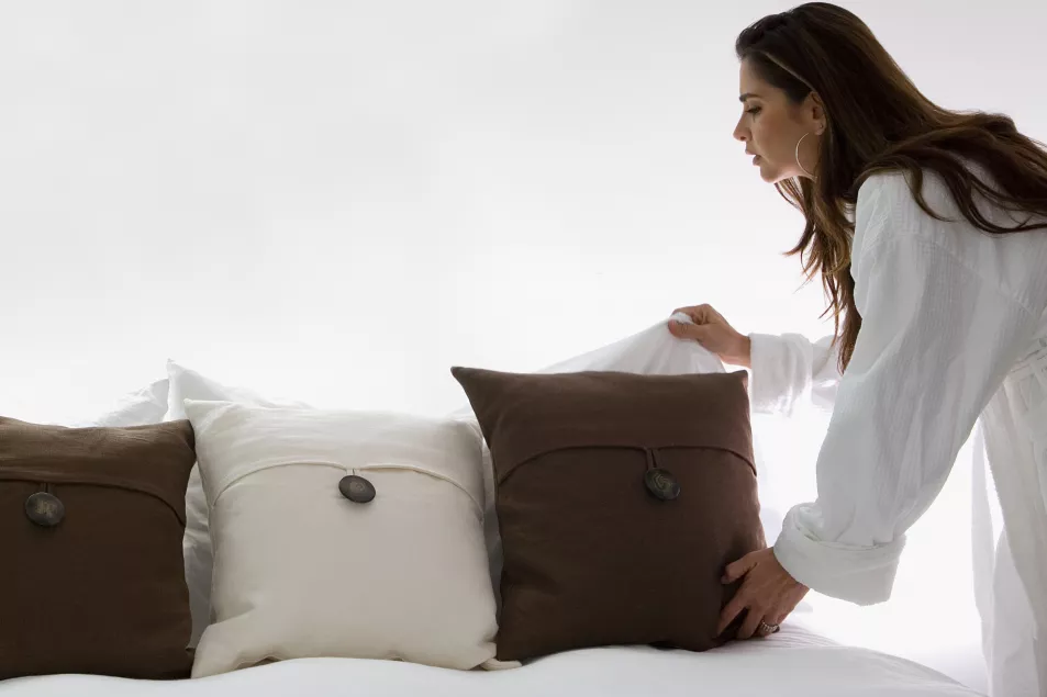 Young woman arranging cushions and making a bed