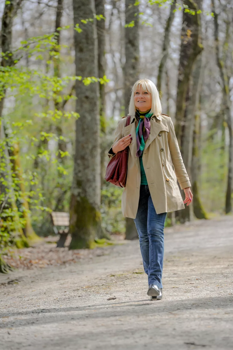 Senior woman walking through a park while smiling 