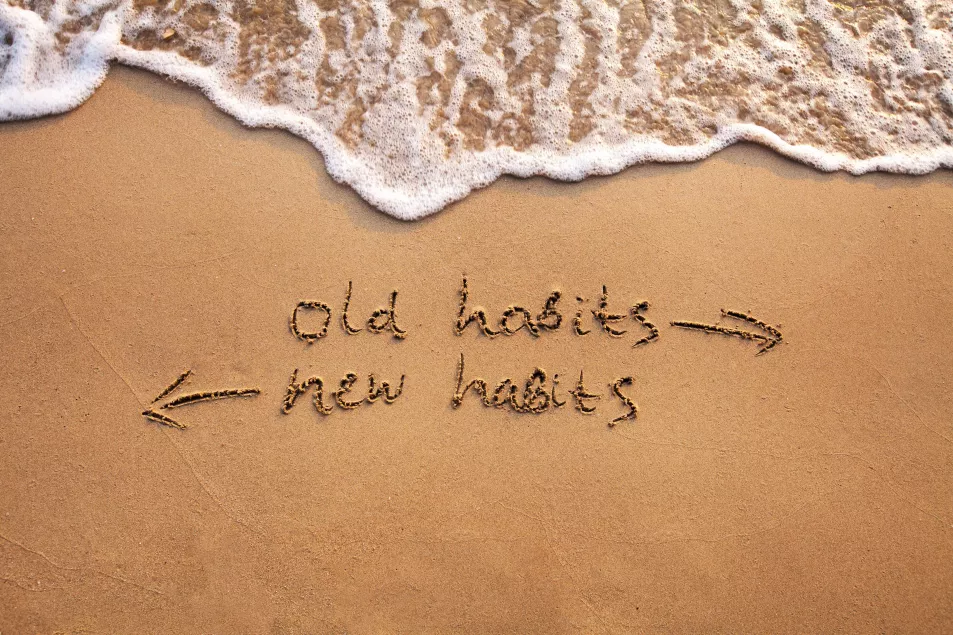 Old habits vs new habits written in the sand 