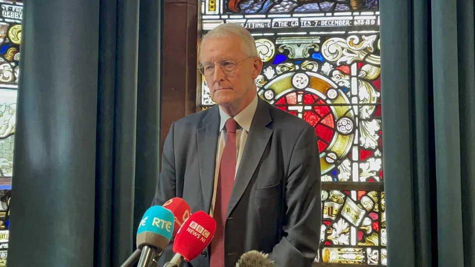 Man in a grey suit in front of a stained glass window