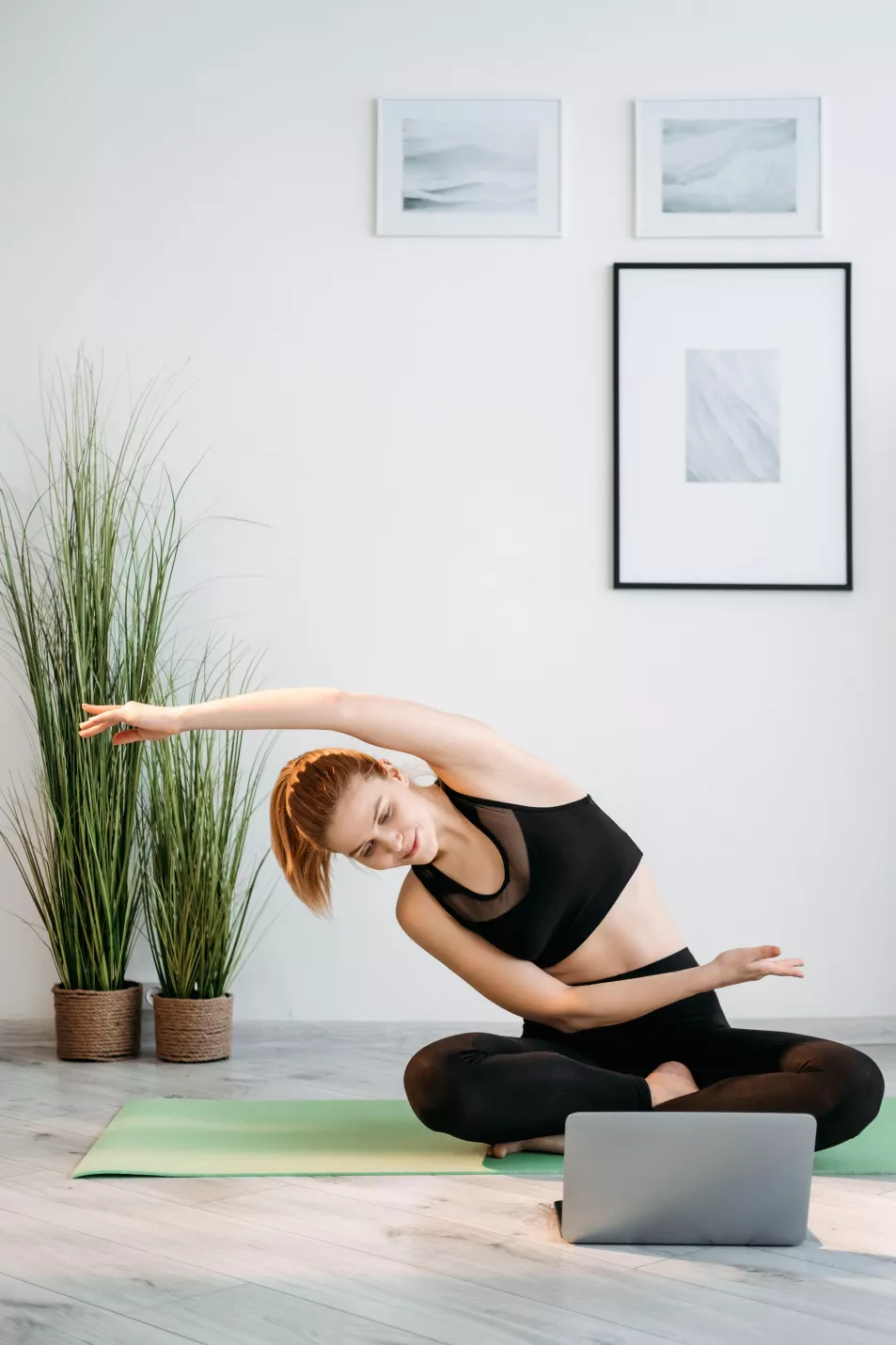 Woman following a yoga routine at home on her laptop 