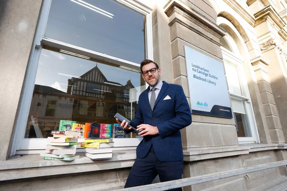 A man in a blue suit with piles of books