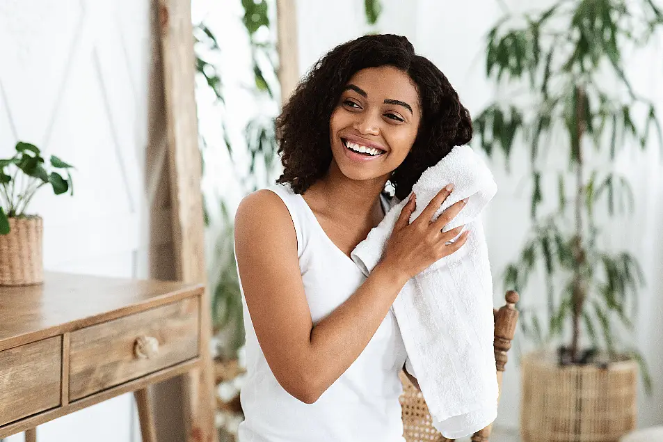 Young woman smiling and drying her wet hair with a towel 