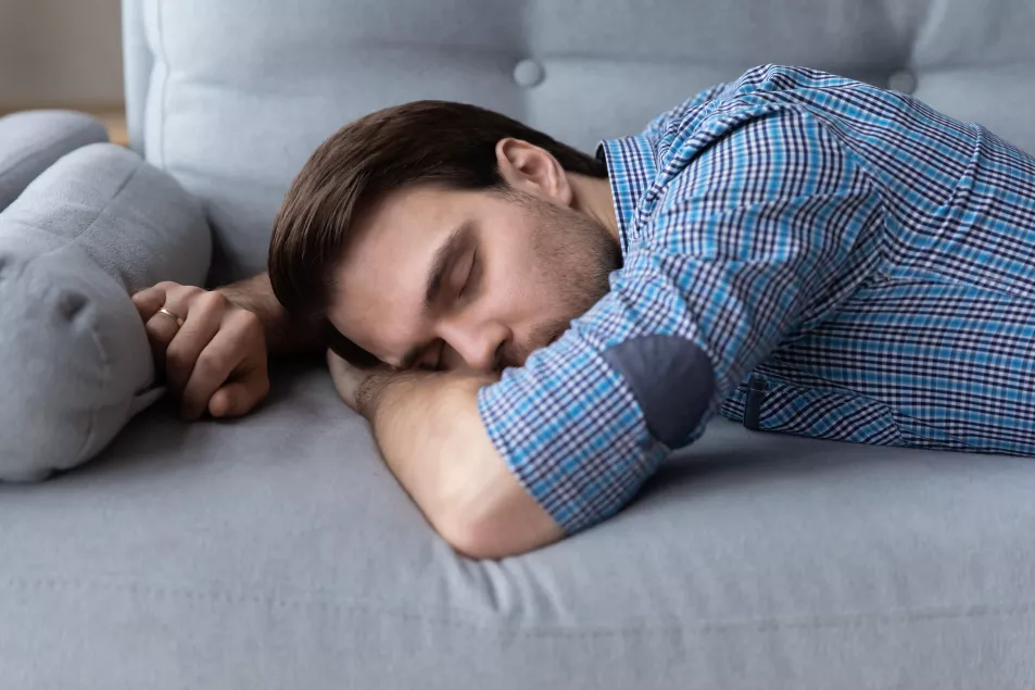 Exhausted young man lying down on sofa