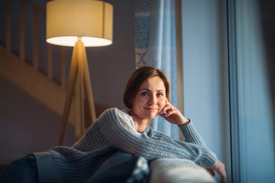 A young woman sitting indoors on a sofa at home 