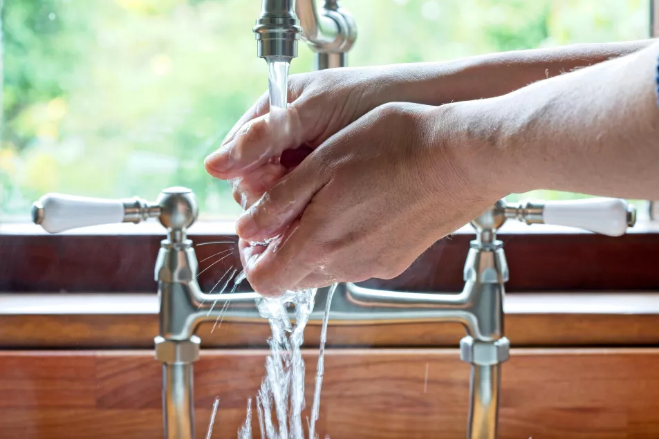 Man washes hands under tap