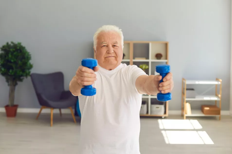 Senior man lifting mini hand weights in his living room