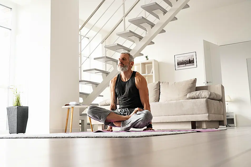 Senior man doing yoga on a mat at home