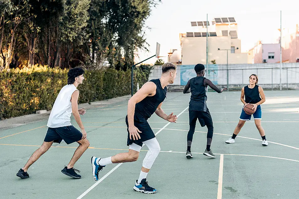 Four friends playing basketball outdoors