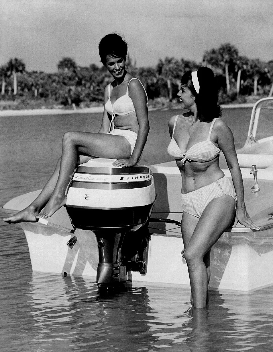 Women smile on a boat in bikinis from 1961