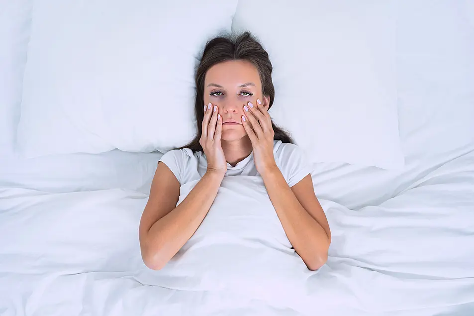 Exhausted woman lying awake in bed