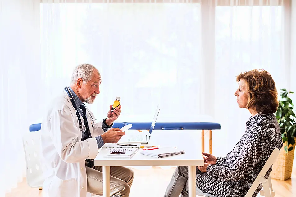 Male GP talking to a senior female patient 