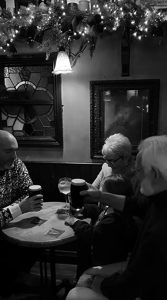 Black and white image of a family of four enjoying a pint at the pub