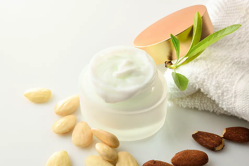 Moisturizing facial cream with almond extract on white table with container with fruits. Elevated view. Horizontal composition.